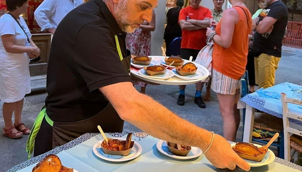 A waiter handing out plates of caponata trapanese